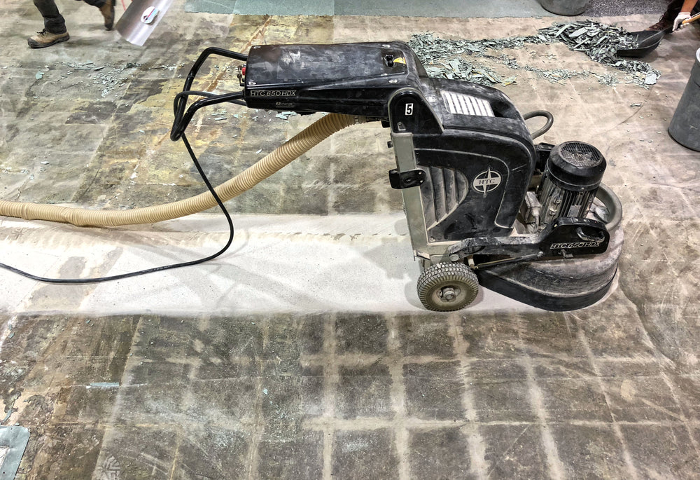 Concrete surface preparation equipment removing old adhesives for flooring installation.
