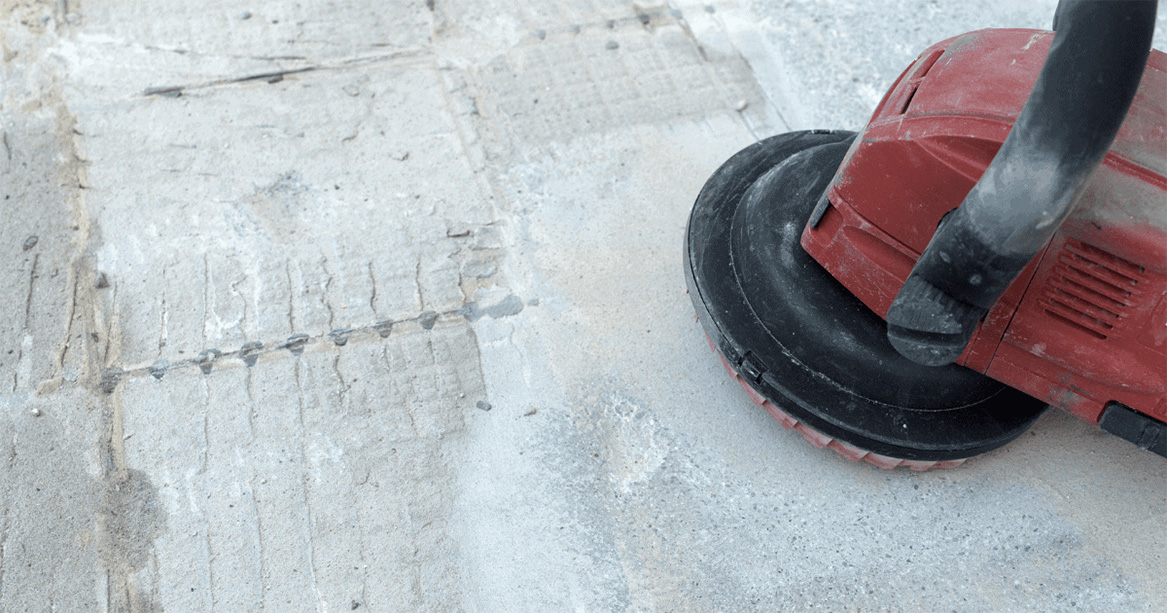 Concrete surface preparation tool in action, grinding and leveling a concrete floor for adhesive removal and flooring installation.