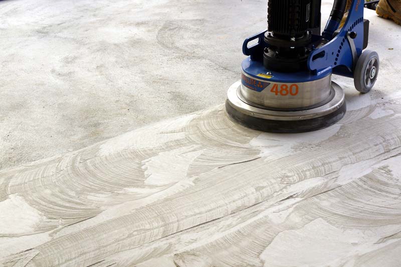 Diamond grinding machine in action on concrete surface, creating smooth and level finish for flooring preparation.