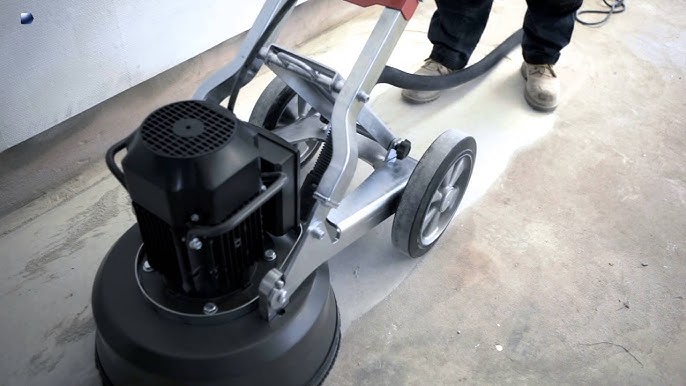 Concrete floor grinder in use for surface preparation, achieving smooth and even surface profile for flooring systems.